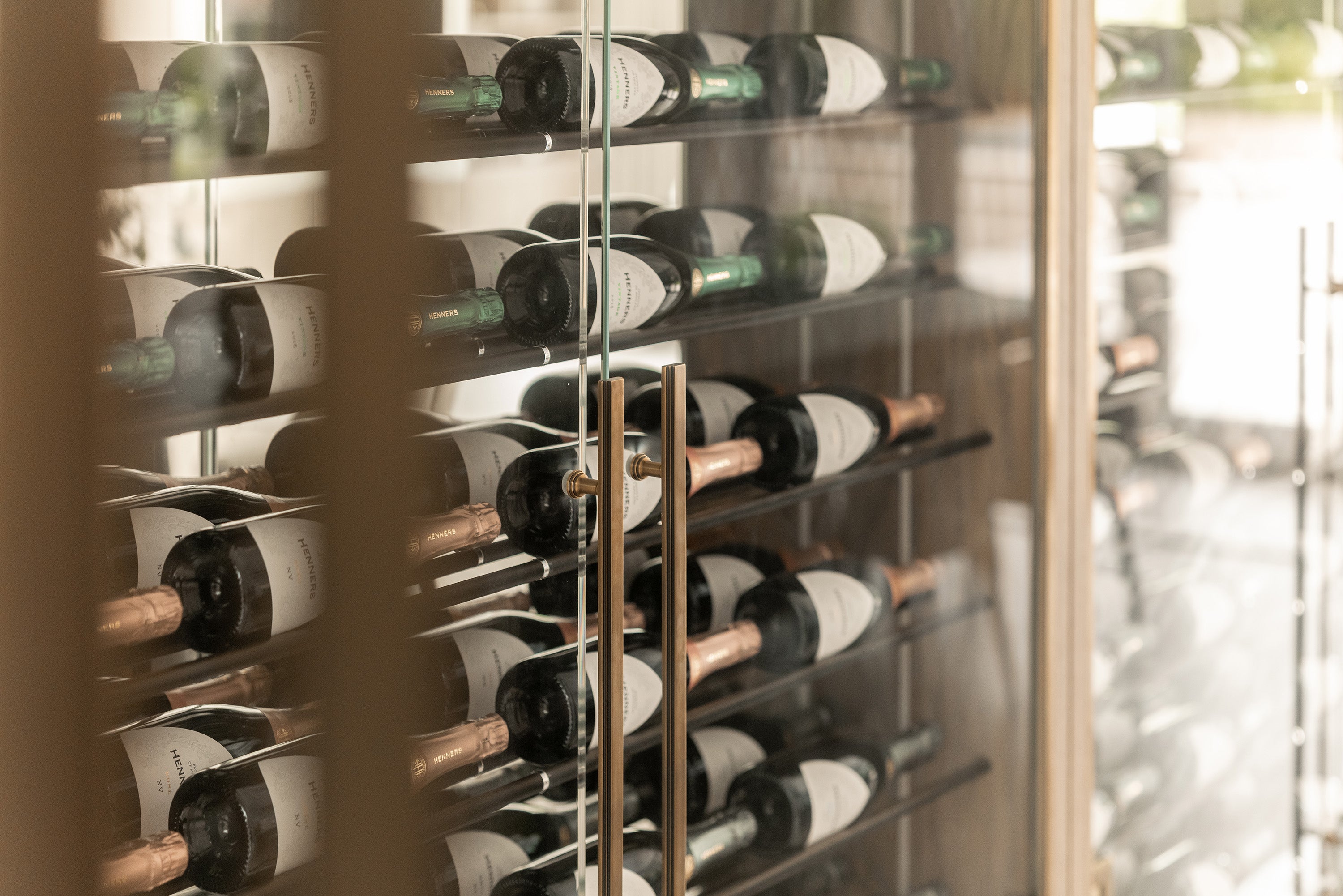 Solid Brass Tanworth Art Deco Appliance Pull in Antique Brass fitted to a glass wine cellar door with bottles of wine behind the glass door.